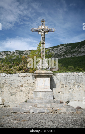 Ein großes Metallkreuz auf einem Steinsockel auf einem ländlichen Bergdorffriedhof in Saou, Drôme, Frankreich. Stockfoto