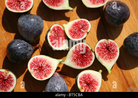 (Ficus Carica) Halbierte und ganze Frische Feigen auf einer hölzernen hacken an Bord, draußen, in der Nähe auf. Stockfoto