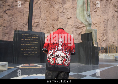 Ein Mann in einem Hemd mit flammender Schädel auf der rückseitigen Pausen in der Nähe der geflügelten Statuen am Hoover-Staudamm Stockfoto