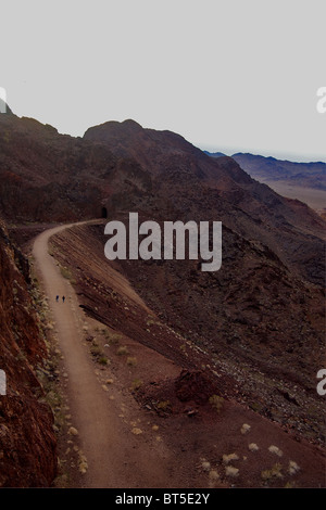 Zwei Menschen gehn auf einen Schotterweg durch die felsige Landschaft in der Nähe von Lake Mead und den Hoover-Staudamm Stockfoto