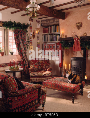 Rot gemusterten Sessel und Hocker neben Holzofen im Wohnzimmer gemütliche Hütte für Weihnachten dekoriert Stockfoto