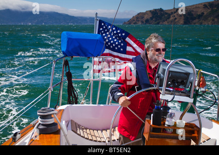 Ein Mann lächelnd, während an der Spitze eines Segelbootes. Stockfoto