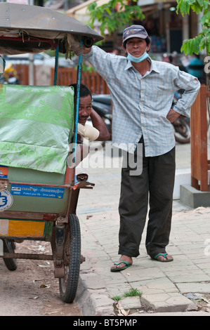 Straßenszene mit Rikscha-Fahrer & Passagier in Siem Reap, Kambodscha Stockfoto