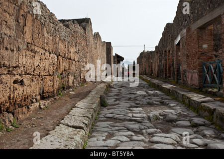 Eine gerade römische Straße grenzt auf jeder Seite von Ruinen der Häuser und Geschäfte, Pompeji, Italien Stockfoto