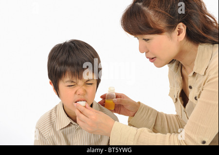 Mutter gibt Sohn medizinisches Getränk Stockfoto