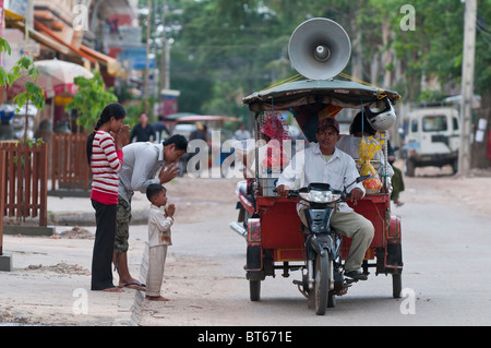 Eine Mobile buddhistische Nonne bietet Segen Pässe durch aus eine Autorikscha auf den Straßen von Siem Reap, Kambodscha Stockfoto