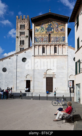 Frau sitzt vor der Basilica di San Frediano, Kirche in Lucca, Toskana, Italien, Europa Stockfoto