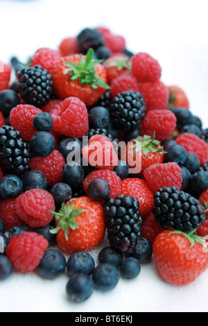 Ein Haufen Erdbeeren Himbeeren Brombeeren und Heidelbeeren vor einem weißen Hintergrund Stockfoto