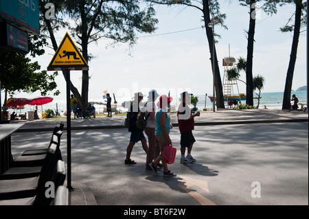 Touristen, die beim Überqueren der Straße neben einem betrunken Menschen Kreuzung Schild von Pa Tong Beach, Phuket, Thailand Stockfoto