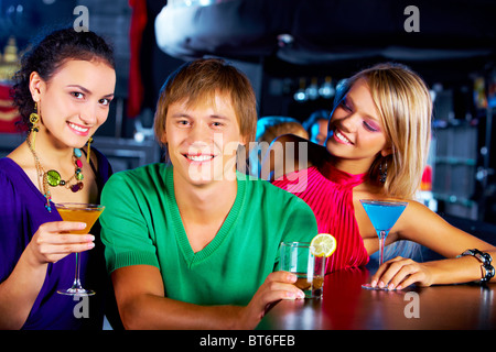 Porträt von zwei Mädchen mit Martini-Gläser rund um glücklicher Kerl im Nachtclub Stockfoto