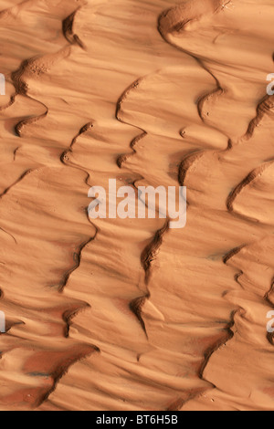 vertikales Bild der rötlichen Sand und Schlamm Wellen durch strömende Wasser Stockfoto