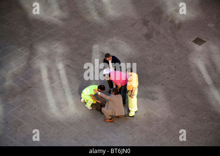 Arbeiter und Beamte Inspektion einen Schacht in den Bürgersteig, Valencia, Spanien Stockfoto