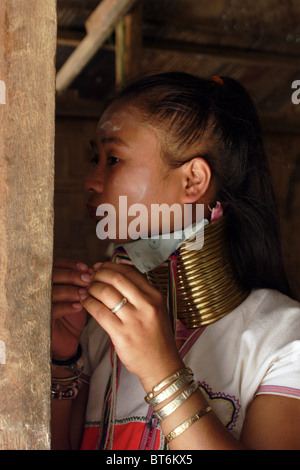 Karen Paduang Longneck Flüchtling Mädchen setzt auf Ohrringe in ihrer Holzhütte in Ban Nai Soi, Thailand. Stockfoto