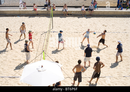 Junge Menschen spielen Beach-Volleyball am Strand von Brighton Stockfoto