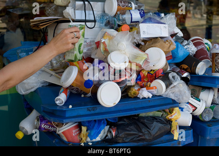 Eine Person platzieren n leer Saft Karton auf einem überquellenden Mülleimer in der Nähe von Brighton Seafront Stockfoto