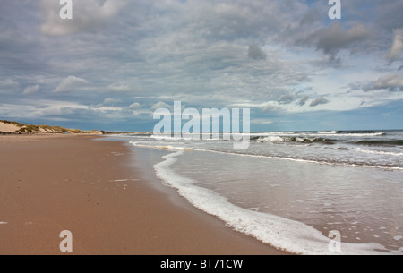 Sonnenstrand mit blauer Himmel, Wolken und brechenden Wellen an der Druridge Bucht, Northumberland Küste, North East England. Stockfoto