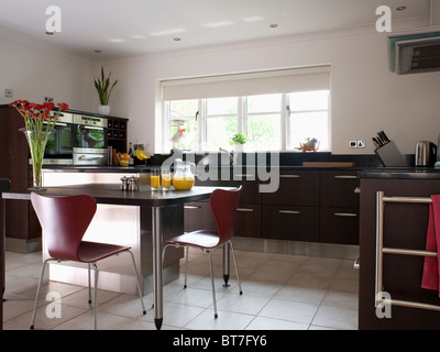 Arne Jacobsen-Stil Stühle am Frühstücks-Bar im modernen weißen Küche Erweiterung mit schwarzen ausgestattete Geräte und weiß gefliesten Fußböden Stockfoto