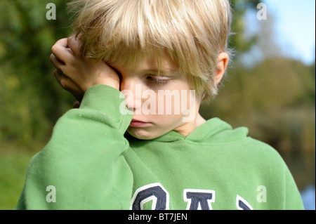 Weinerlich, schmollen, satt blonden kleinen Jungen in eine grüne Spitze draußen Stockfoto