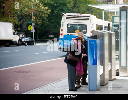 Pendler kaufen Tarife vor dem Einsteigen in eines Bus-Service wählen Sie Bus auf Second Avenue in Midtown in New York Stockfoto