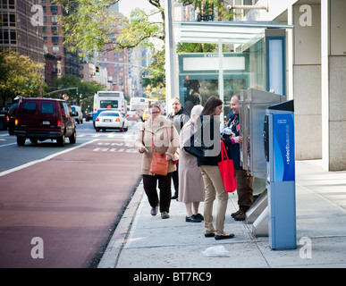 Pendler kaufen Tarife vor dem Einsteigen in eines Bus-Service wählen Sie Bus auf Second Avenue in Midtown in New York Stockfoto