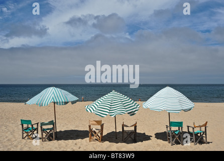 Drei Sonnenschirme mit Stühlen auf dem Sand am Strand von Figueira da Foz in Portugal Stockfoto