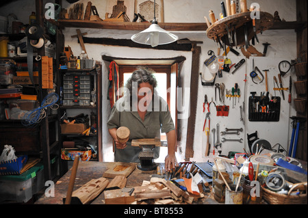 Handwerker in ihrem Holzschnitzerei Workshop umgeben von Werkzeugen, Portugal Stockfoto