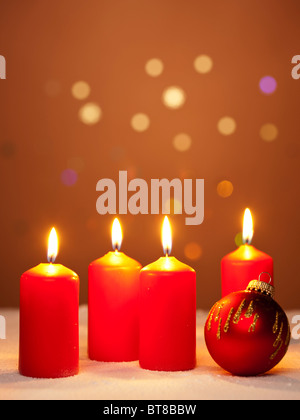 vier brennende Advent Kerzen und eine rote Weihnachtskugel Stockfoto