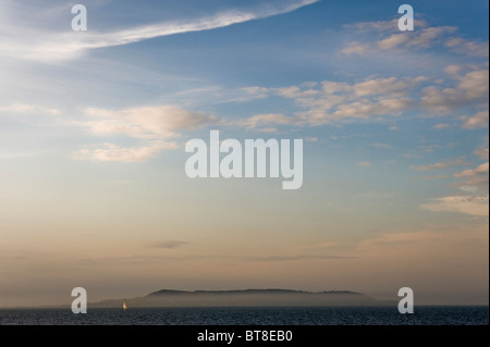 Eine einzelne Yacht in der Bucht von Dublin mit Howth Head im Hintergrund von Dun Laoghaire an einem Sommerabend in Dublin, Irland gesehen. Stockfoto