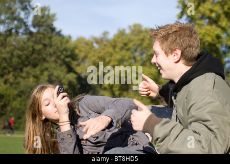 sechzehn Jahre alte geben Daumen hoch für seine Freundin für ein Foto in einem park Stockfoto