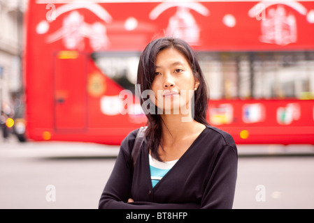 Porträt einer jungen orientalischen Frau (Koreanisch asiatische) auf den Straßen von London mit einem komfortablen Bus im Hintergrund Stockfoto