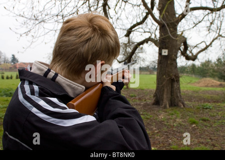 Junge auf Ziel am Baum mit Luftgewehr schießen Stockfoto