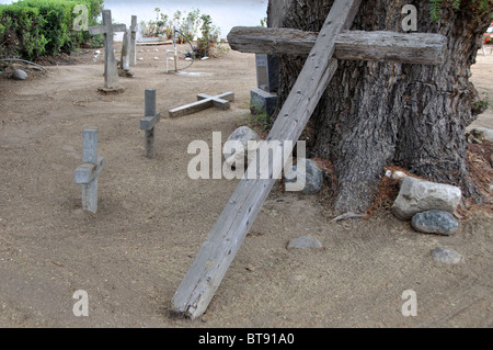 An einem Kalifornien-Pfefferbaum in einem indischen Friedhof an der MIssion San Antonio de Pala gelehnt Holzkreuz Stockfoto