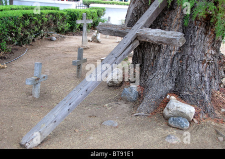 An einem Kalifornien-Pfefferbaum in einem indischen Friedhof an der MIssion San Antonio de Pala gelehnt Holzkreuz Stockfoto