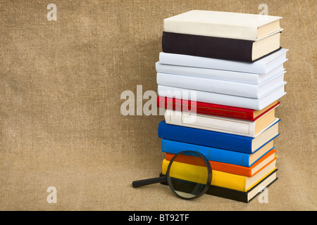 Große Haufen Bücher und Lupe auf Leinwand Stockfoto