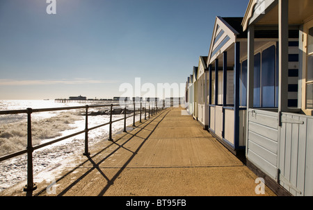 Strandhütten auf Southwold Promenade mit dem Pier im Hintergrund Stockfoto