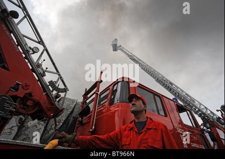 Feuerwehrmann nach oben neben einem Feuerwehrauto mit einer Ausziehleiter Stockfoto