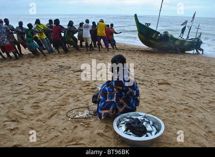 Fischer ziehen in einem Fischerboot am Strand von Sassandra, Elfenbeinküste, Westafrika Stockfoto