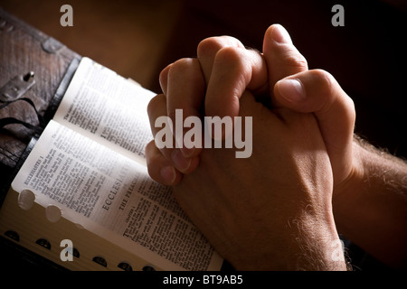 Betende Hände auf eine aufgeschlagene Bibel Stockfoto