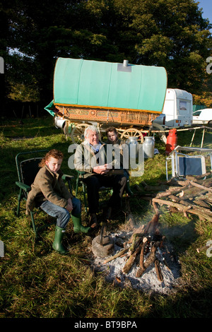 Ein alter Zigeuner Mann sitzt mit seinem Enkel vor seinem Feuer und seinem Pferd gezogenen Bogen gekrönt Wohnwagen. DAVID MANSELL Stockfoto