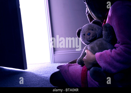 Junges Mädchen sitzend hält einen Teddybär, Ansicht von hinten. Mod-rel Stockfoto