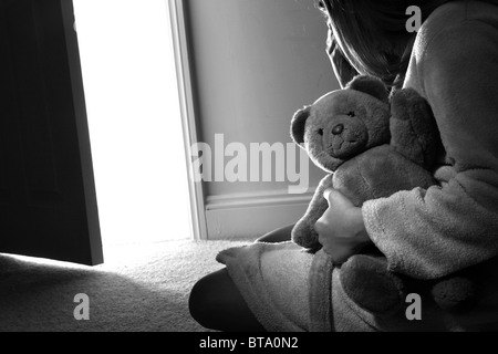 Junges Mädchen sitzend hält einen Teddybär, Ansicht von hinten. Stockfoto