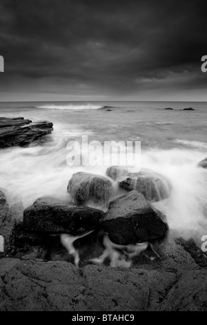 Wellen über Felsen bei Ebbe, gegen Bay in der Nähe von Whitby, North Yorkshire Coast Stockfoto