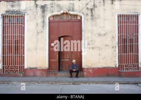 TRINIDAD: KUBANISCHE MANN SITZT IN TÜR Stockfoto