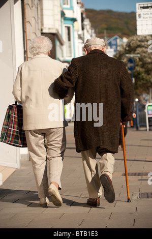 Eine Rückansicht von einem älteren Ehepaar gehen Arm in arm Stockfoto