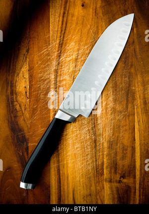 Große Edelstahl Santoku Kochmesser auf ein Schneidbrett aus Holz Stockfoto