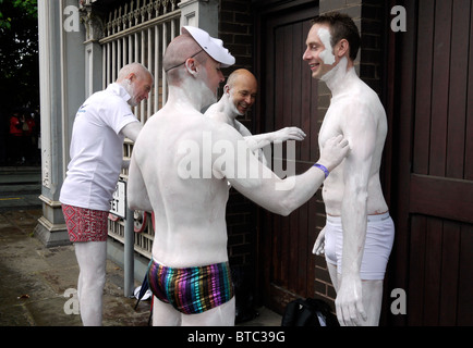 Gay Men genießen es, fotografiert zu werden, während sie vor der Manchester Pride Parade 2010 im Stadtzentrum, England, Körperfarbe auftragen Stockfoto