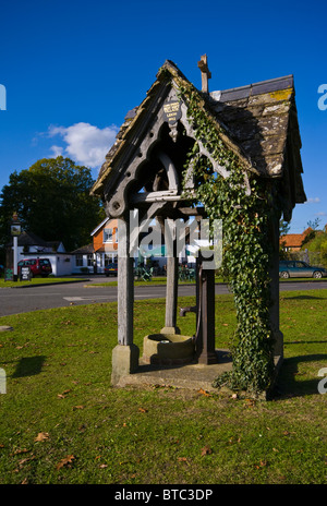 Old Village Pump auf Leigh grün mit dem Pflug-Pub im Hintergrund Surrey England Stockfoto