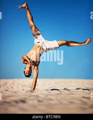 Junge Sportler am Strand. Am blauen Himmelshintergrund. Stockfoto