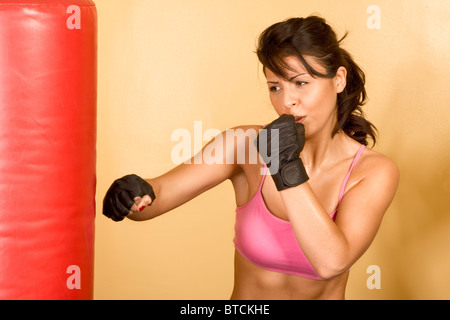 Attraktive weibliche Kickboxen mit roten Boxsack Stockfoto