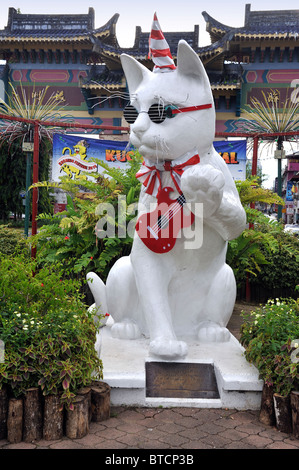 Die weiße Katze am Eingang nach Kuching, Wahrzeichen der Stadt, während eines Festivals konkurrieren mit rotem Hut, kühlen Schatten und Gitarre Stockfoto